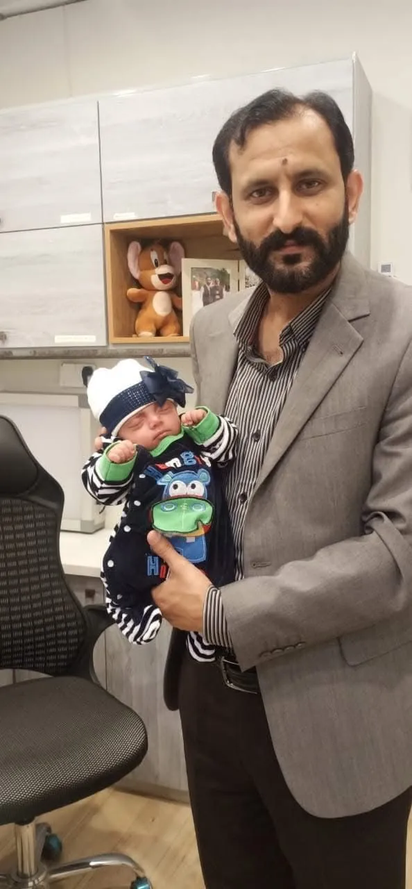Dr. Raja Imran child specialist in Rawalpindi holding a baby during checkup